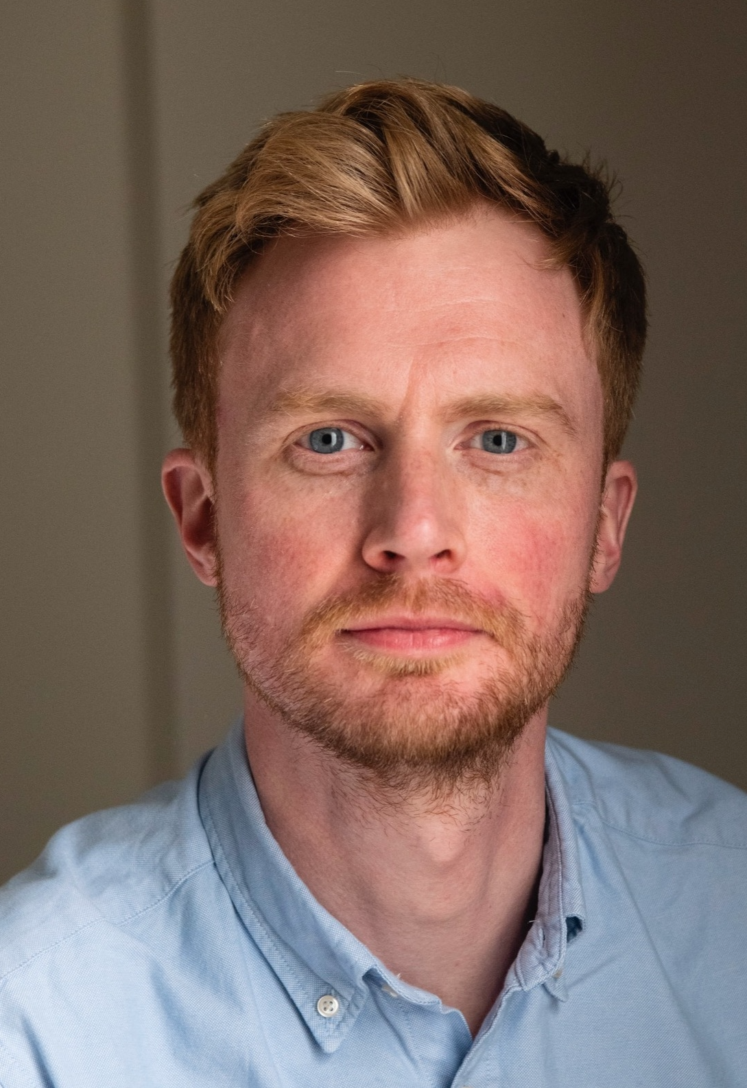 A man with a short beard wearing a shirt with a buttoned collar