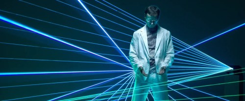 A man in a white suit surrounded by lasers