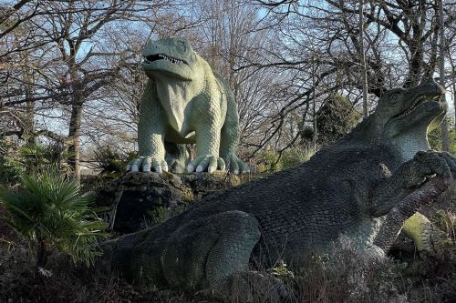 Two concrete models of dinosaurs in an outdoor setting
