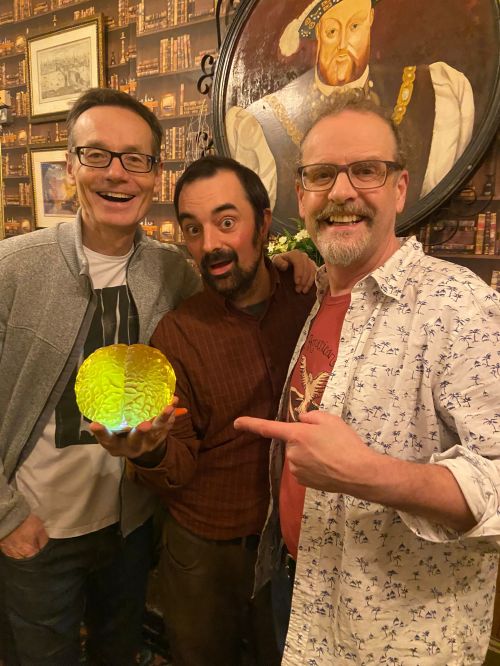 Three smiling men and a glowing model of Einstein's brain