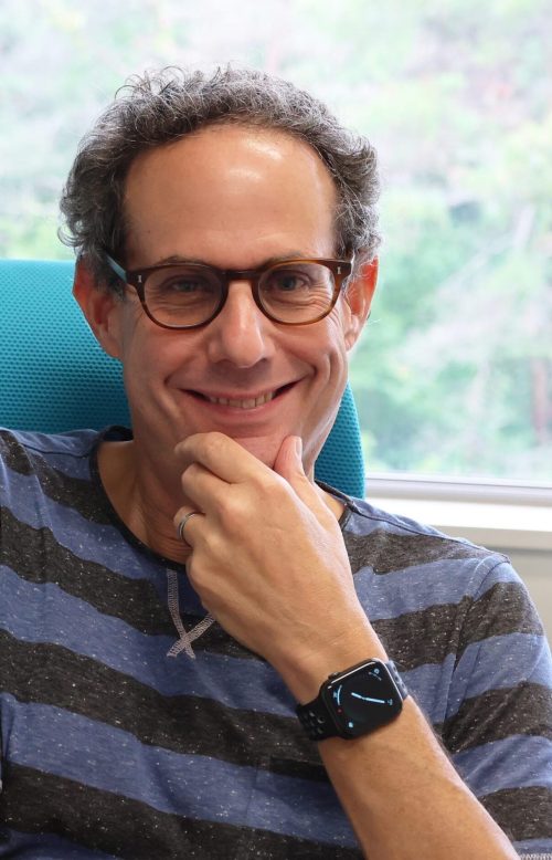 A man wearing glasses sitting on an office chair