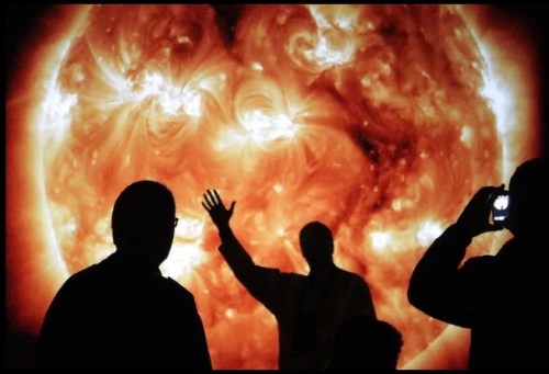 Silhouettes of people standing in front of a giant sun disk