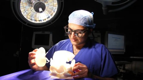 A gowned surgeon looking at a 3D model in the operating theatre