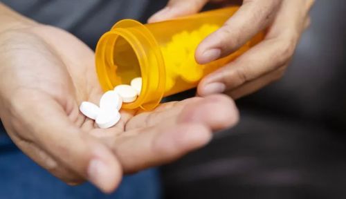 Somebody shaking round, white pills out of a bottle