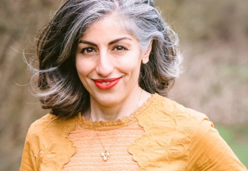 A smiling woman with grey hair and r3ed lipstick
