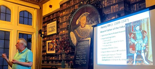 A man in a pub. A portrait of henry VIII and projected image of henry